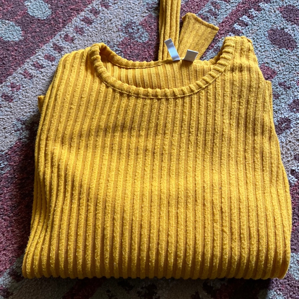 Yellow long sleeve shirt with a tie on the bottom.